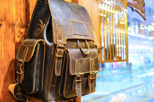 Leather backpacks and briefcases hang on the wall. The concept of stylish leather products. Bags, purses and belts. — Stock Photo, Image