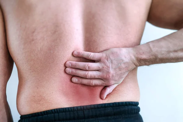 Rode rugpijn op een lichte achtergrond. Geïsoleerde achtergrond. Sportfysiotherapie. Concept van fysiek trauma. Het begrip pijn. — Stockfoto