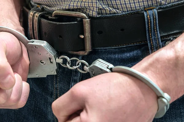 Преступник был задержан полицией. Руки в наручниках сжаты в кулаки. . — стоковое фото