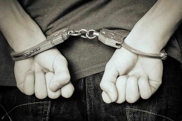 Monochrome image. The criminal was detained by the police. The handcuffed hands clenched into fists. — Stock Photo, Image