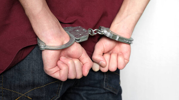 The criminal was detained by the police. The handcuffed hands clenched into fists.