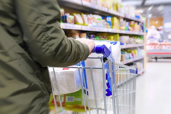 Productos de supermercado, artículos para el hogar. Carro de mercancías, la chica va a lo largo de las filas de la tienda . — Foto de Stock