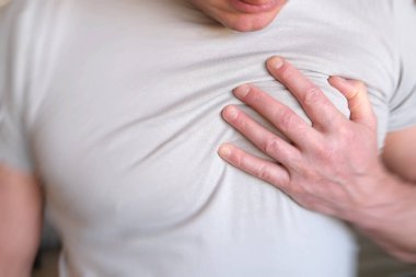 Adam göğsüne tutundu. Beyaz bir arka planda kalp krizi anjini. Hasta herif. Tıbbi muayene. Kalp hastalığı.
