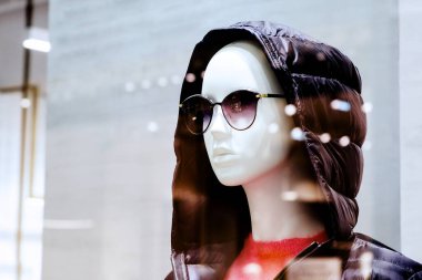 Mankenin kafasında kapüşon olan bir ceket. Alışveriş merkezinde bir butik. Mağaza önü. Satılık.