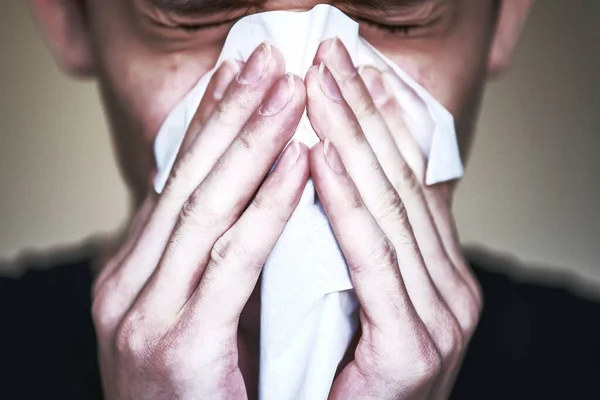 Picture of the disease. A person with symptoms of the disease presses a handkerchief to his face. Sneezing, bouts of coughing