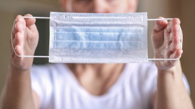 Kişisel koruyucu ekipman. Kızın ellerinde koruyucu tıbbi maske var. Bir salgın sırasında virüsün yayılmasını önleme kavramı.