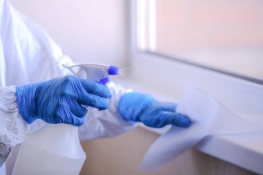 Koruyucu giysi giyen bir uzman hijyenik tedavi uyguluyor. Dezenfeksiyon önleme.