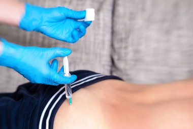 Tıbbi eldivenli bir doktor, hastaya şırıngayla ilaç verir. Kalçaya kas içi enjeksiyon.