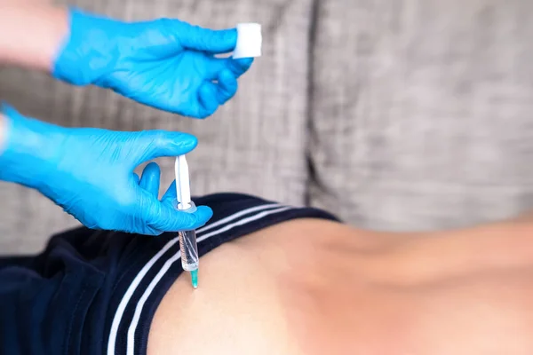 Tıbbi eldivenli bir doktor, hastaya şırıngayla ilaç verir. Kalçaya kas içi enjeksiyon.