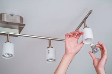 Çorbaya yanmış bir halojen lamba yerleştiriyorum. Adam bir eliyle abajuru tutuyor ve diğer eliyle lambayı tabanına yerleştiriyor.