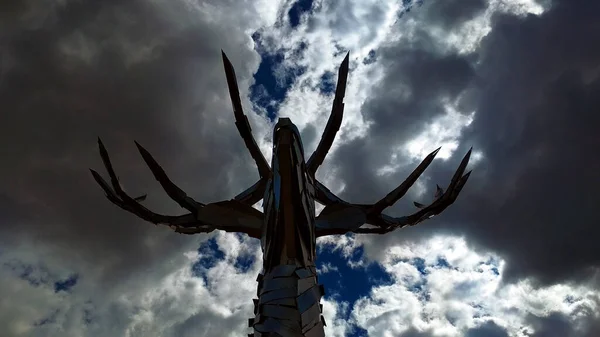 metallic figure of a deer\'s head against a cloud