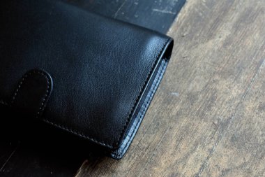 Hafif ahşap arka planda siyah deri cüzdan.