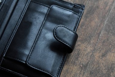 Hafif ahşap arka planda siyah deri cüzdan.