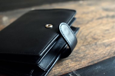 Hafif ahşap arka planda siyah deri cüzdan.