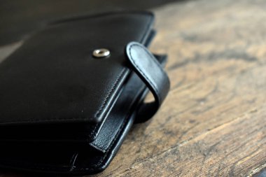 Hafif ahşap arka planda siyah deri cüzdan.