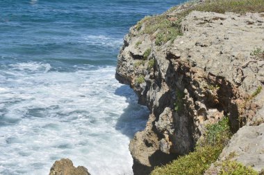 Mavi dalgalar yüksek kayalıklara çarpıyor