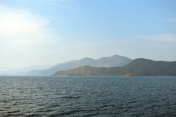 Dağlar, kayalar, deniz kıyısındaki ağaçlar
