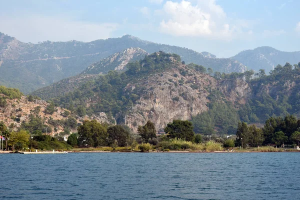 Dağlar, kayalar, deniz kıyısındaki ağaçlar