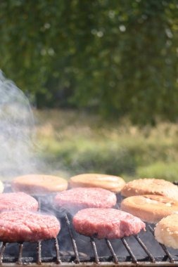 Bahçedeki ızgarada hamburger yapma süreci.