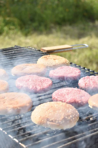 the process of making burgers on the grill in the garden