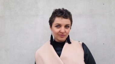 Kısa kıvırcık saçlı ve parlak mavi gözlü çekici genç bir kadın kameraya bakıyor ve baştan çıkarıcı, yavaş çekimde gülümsüyor, Lgbt