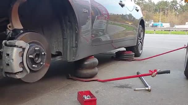 La voiture est sur deux vérins, disques de frein nus, remplacement des roues, montage des pneus — Video