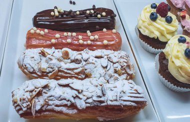 Cam kutunun arkasında kremalı ve dutlu ekekler ve kekler var.