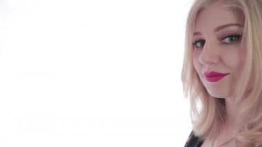 Uzayı kopyala Çerçevenin kenarında kırmızı dudakları olan genç ve çekici bir sarışın. Bir el boşluğu tutarken, diğer el başparmağını kaldırıyor. Kız onaylayıcı bir şekilde başını sallıyor. Beyaz arka plan. Video düzenleme