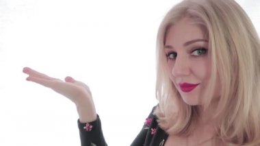 Uzayı kopyala Çerçevenin kenarında kırmızı dudakları olan genç ve çekici bir sarışın. Bir el boşluğu tutarken, diğer el başparmağını kaldırıyor. Kız onaylayıcı bir şekilde başını sallıyor. Beyaz arka plan. Video düzenleme