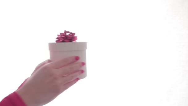 Κοντινό πλάνο. Γυναικεία χέρια δίνουν από χέρι σε χέρι λευκό κουτί δώρου με κόκκινο τόξο σε λευκό φόντο. Απομονωμένοι. Ημέρα του Αγίου Βαλεντίνου, Παγκόσμια Ημέρα της Γυναίκας, γενέθλια, εορταστική έννοια. Προσομοίωση — Αρχείο Βίντεο