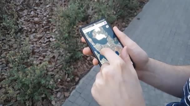 길거리에서 스마트폰을 사용하는 남성 손의 맨 위 사진. 현대 과학 기술의 개념인 모바일 인터넷의 도움을 받아 지도를 사용하는 남자 — 비디오