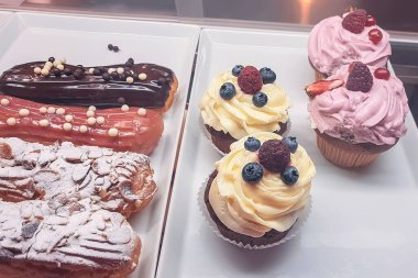 Cam kutunun arkasında kremalı ve meyveli kekler, lezzetli bir tatlı.