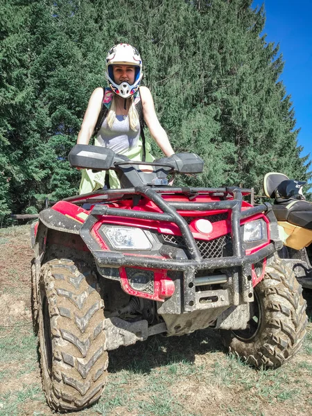 Mujer joven con casco en una bicicleta Quad roja en un bosque — Foto de Stock