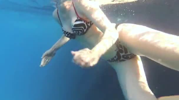 Young slender girl in a bikini with big Boobs swimming in the clear sea waters. Underwater shoot of female body. The concept of leisure, sea vacation, slow motion — Stock Video