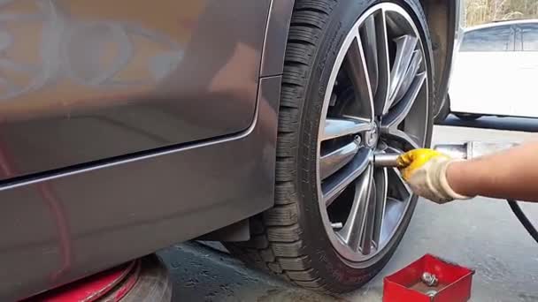 Kiev, Ucrania 18 de agosto de 2019. el mecánico desenrosca los tornillos con un taladro eléctrico para quitar y reemplazar la rueda — Vídeo de stock