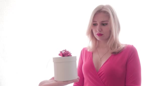 Joven mujer hermosa en vestido rojo triste. Las manos masculinas le entregan un regalo, ella se sorprende, abre el regalo y salta de alegría. Abrazos caja regalo, sonríe y cierra los ojos con felicidad — Vídeo de stock