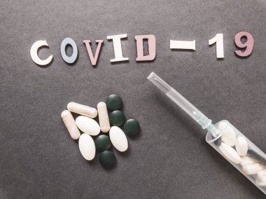 İlaç ve şırınga yığınının arkasındaki Covid-19 yazısını. Haplarla dolu. Coronavirus aşısı arama konsepti