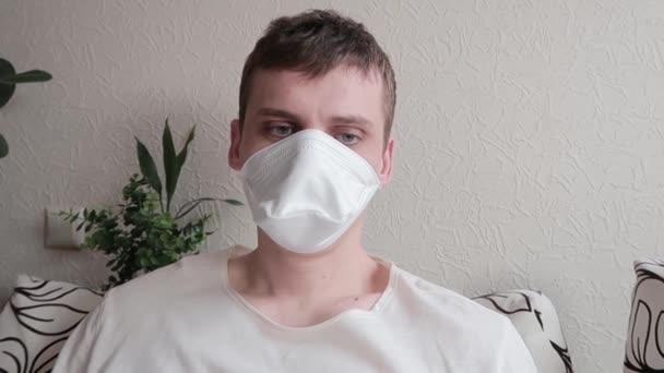 Concept of disease. Man in the mask looks wearily into the camera, coughing and looking at camera again. Colds, flu or a virus — Stock Video