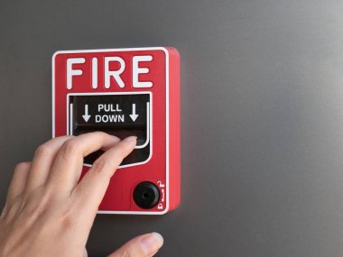 gri arka plan üzerinde kırmızı yangın alarm çekerek adamın elini
