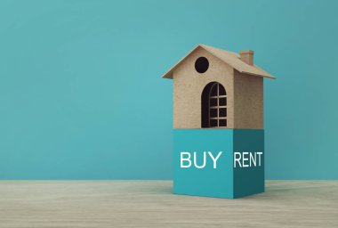 Buy or Rent 'in ahşap masada olduğu yaratıcı bir ev modeli fikri. Emlak yatırımı gayrimenkul ve konut kredisi finansal konsepti.