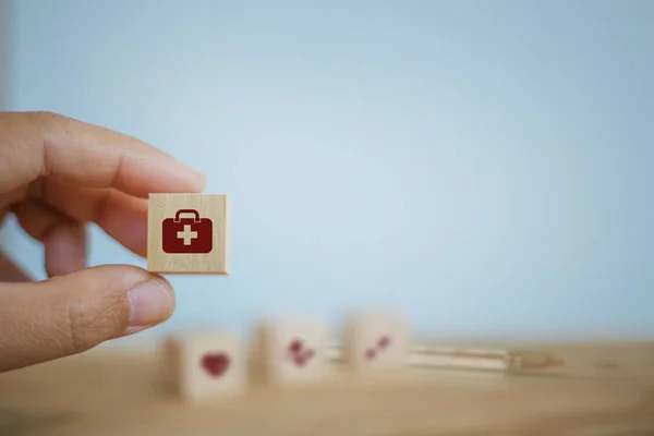 Medical treatment / Medical operating system / Healthcare concept : Hand chooses wooden cube blocks with icon health care medical on table wooden background. Health and medical insurance