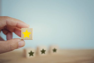 Business success: Hand chooses wooden yellow star shape on table. The best excellent business services rating customer experience concept.