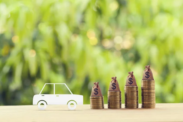 Finans ve araba kredisi, yeniden finansman, nakit geri ödeme, yatırım ve iş konsepti: Karton model sedan araba ve ABD dolarlarıyla yükselen bozuk paralar.