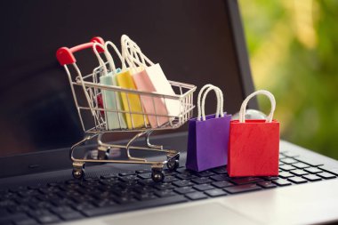 Çevrimiçi alışveriş, e-ticaret konsepti: Tramvayda kağıt alışveriş torbaları veya doğal yeşil arka planda alışveriş arabaları. İnternet üzerinden ürün satın almak yabancı ülkelerden mal satın alabilir