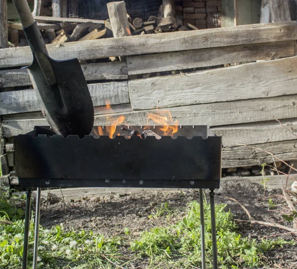 Barbekü için kömürleri hazırlanması. Büyük bir kürek ahşap yakma ile karıştırılır. Küçük bir mangal. Yangın