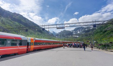 Myrdal İstasyonu, Norveç - 21 Temmuz 2018: Resimli yeşil tepelerin arka planında uzun kırmızı tren. Biniş yolcuları.
