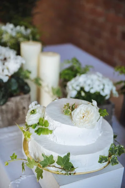 Wedding cake. White small flowers in green leaves on a table with candlesflowers in boxes wedding table decoration