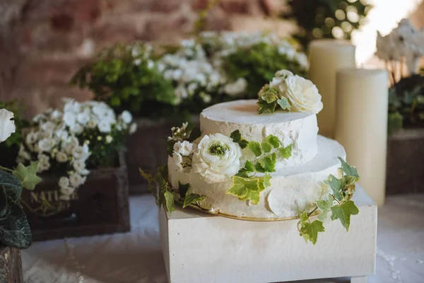 Wedding cake. White small flowers in green leaves on a table with candlesflowers in boxes wedding table decoration