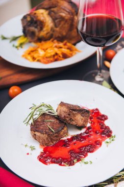 meat medallions on a beautiful background with red wine and a shank in the background