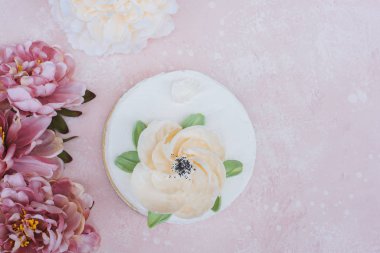 cream cake with a large flower on a pink background top view